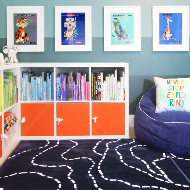 Corner bookshelf in kids' room with books organized by color