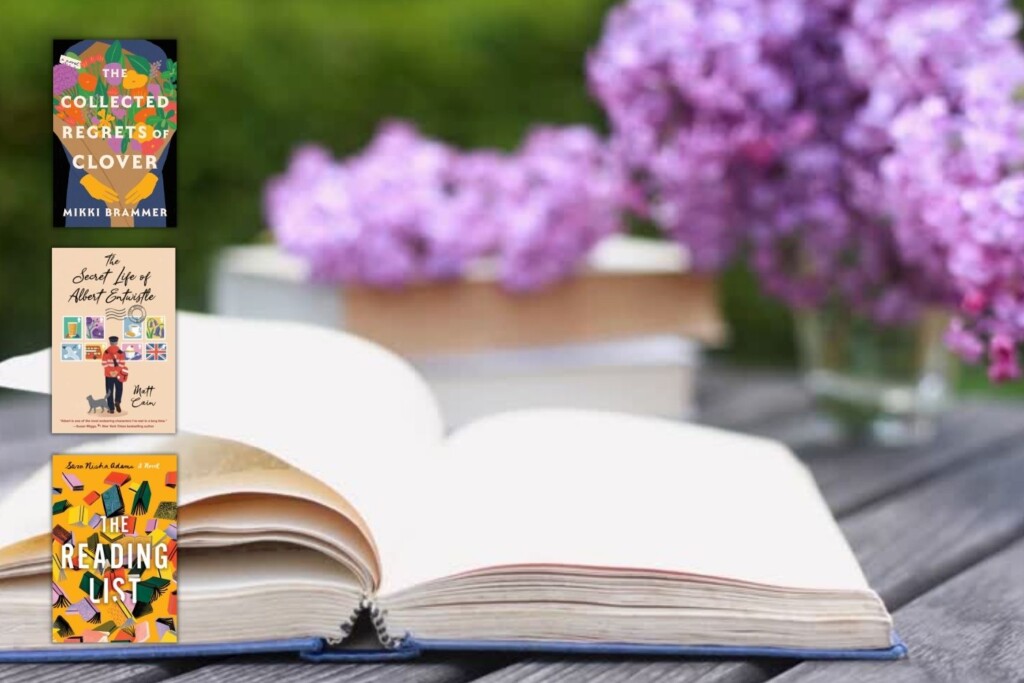 Open book on a wood table with purple flowers in the background and three book covers down the right side of the image