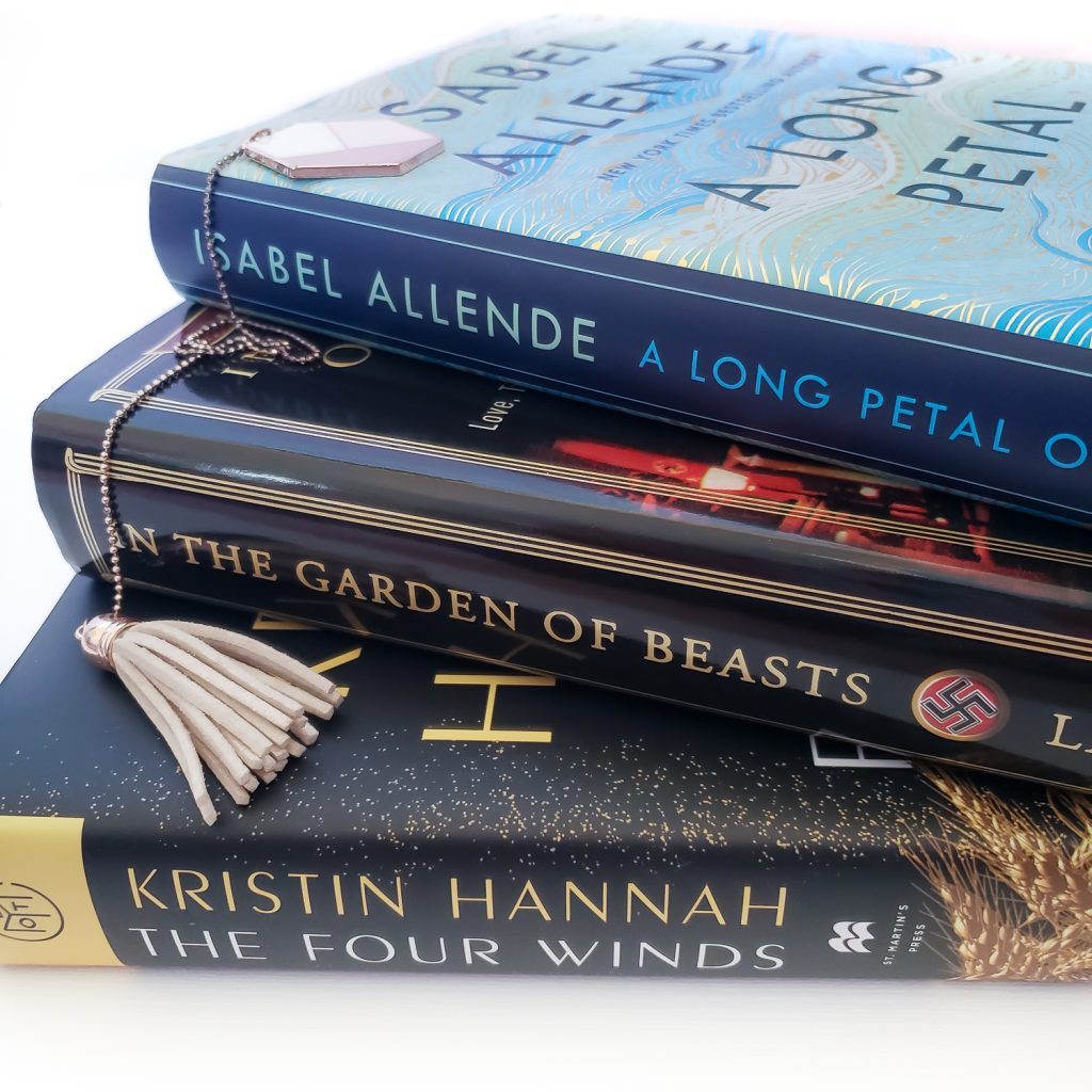 Stack of books with dark spines, A Long Petal of the Sea on top