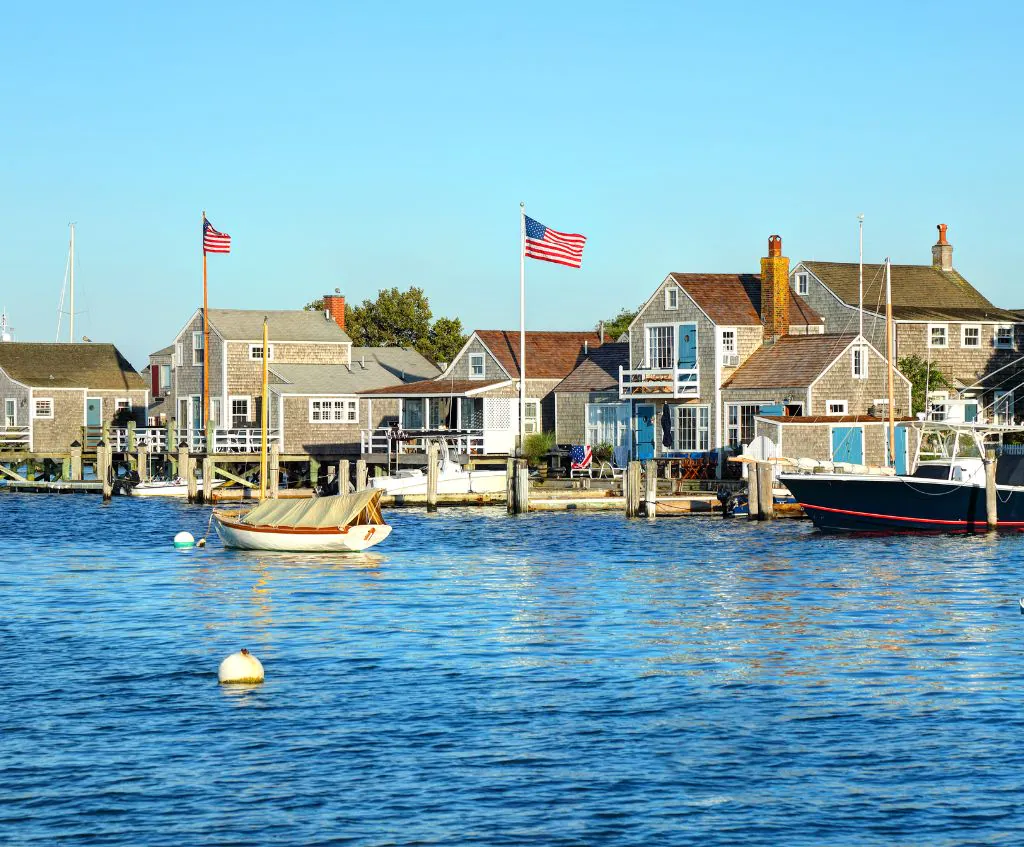 Photo of Nantucket with houses, American flags, and boats tied to the docks