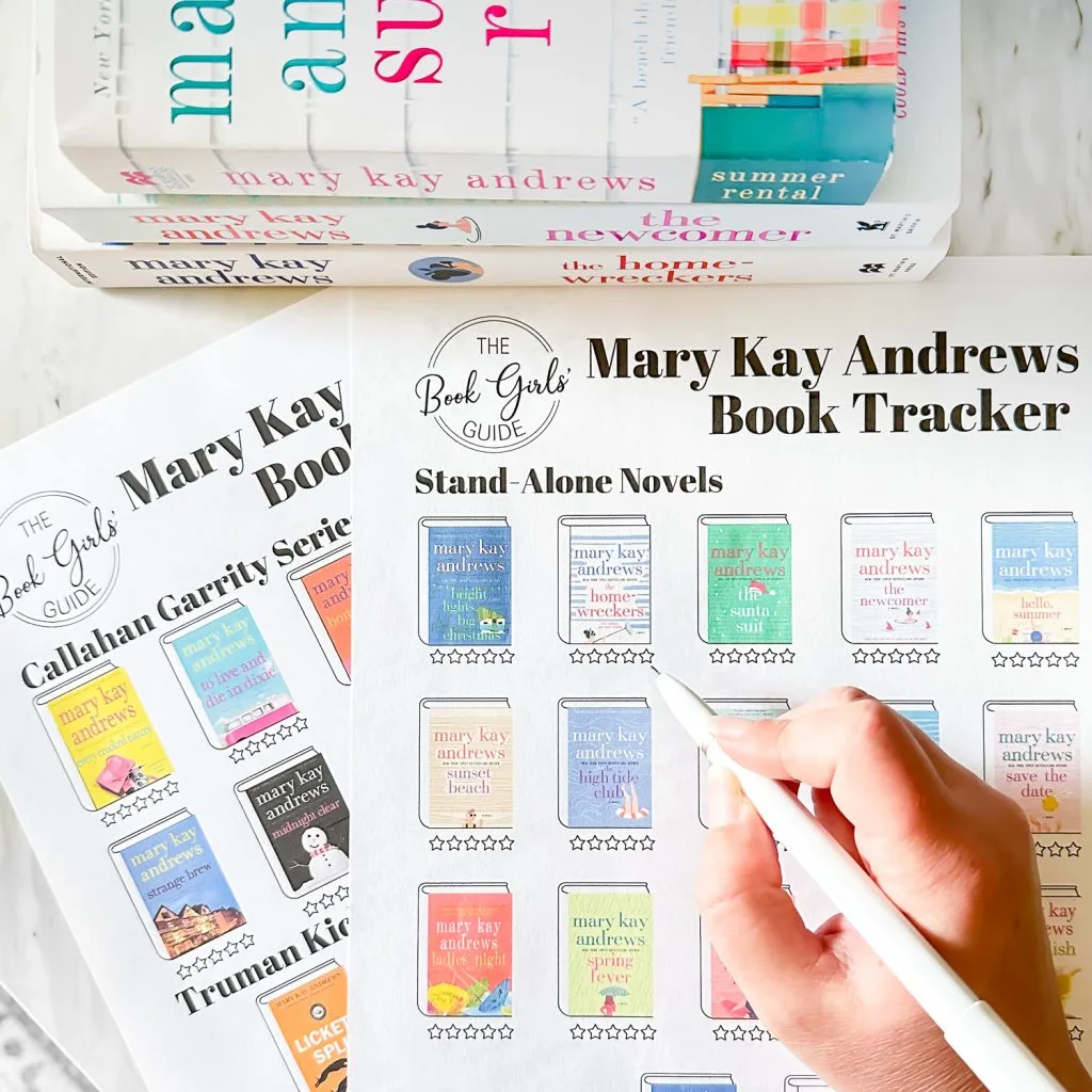 Photo of a hand holding a pen filling out a Mary Kay Andrews books in order printable with a stack of three Mary Kay Andrews books at the top of the image