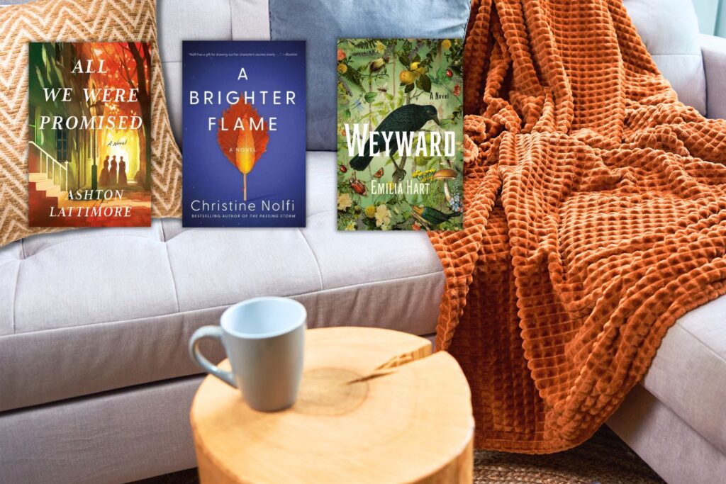 A couch with an orange pillow and blanket, a side table with a coffee mug, and three book covers with cozy fall reading vibes