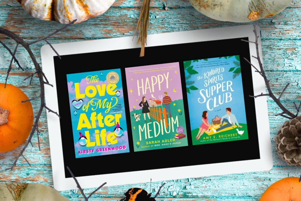 An ipad with three Halloween romance covers on the screen surrounded by pumpkins all laying on a blue wood background