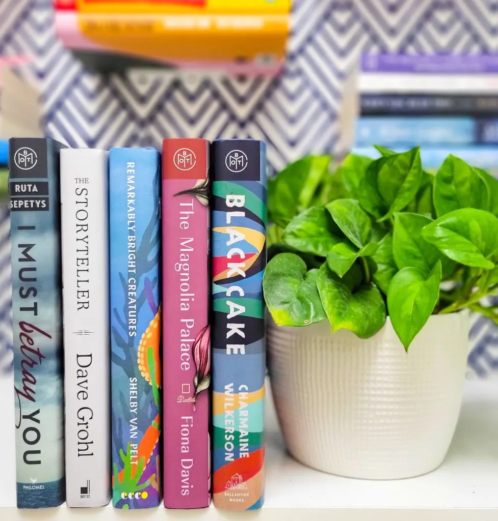 Bookshelf showing spines & a plant