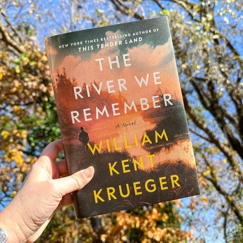 The River We Remember book cover in photo in front of trees