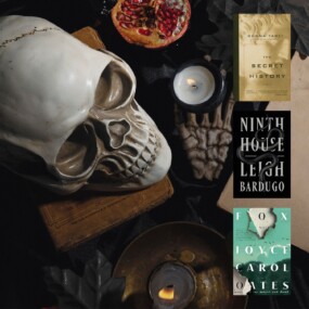 Flatlay image of old books, a skull, candles, and black leaves overlayed with three Dark Academia book covers