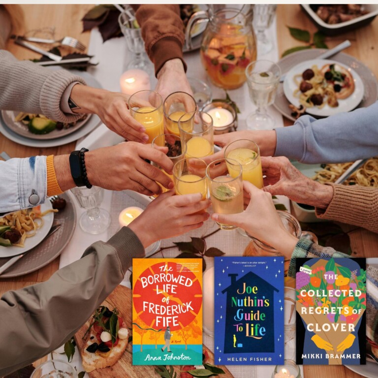 Many hands cheers-ing over a full table of food with 3 book covers