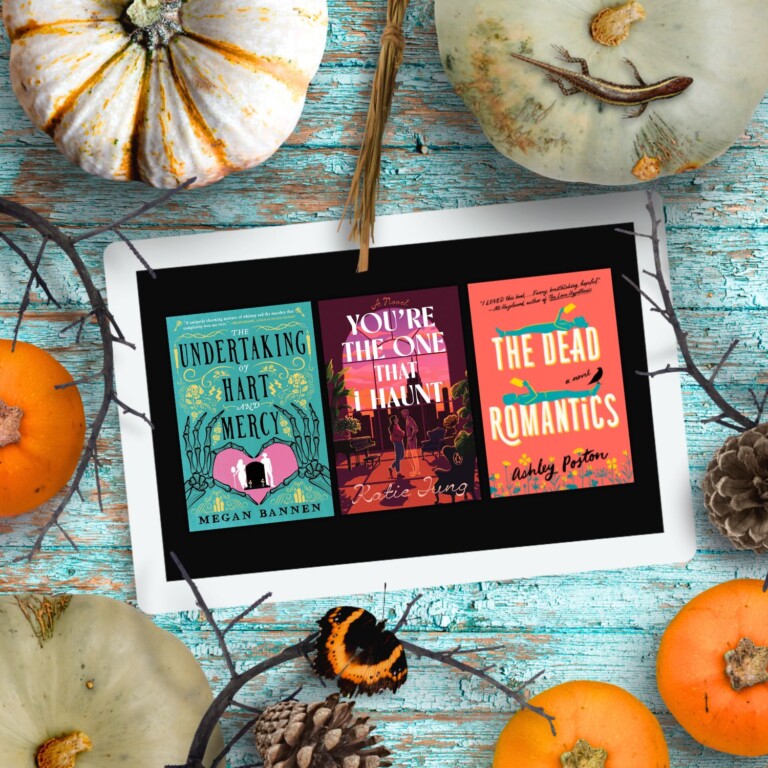 An ipad with three Halloween romance covers on the screen surrounded by pumpkins all laying on a blue wood background