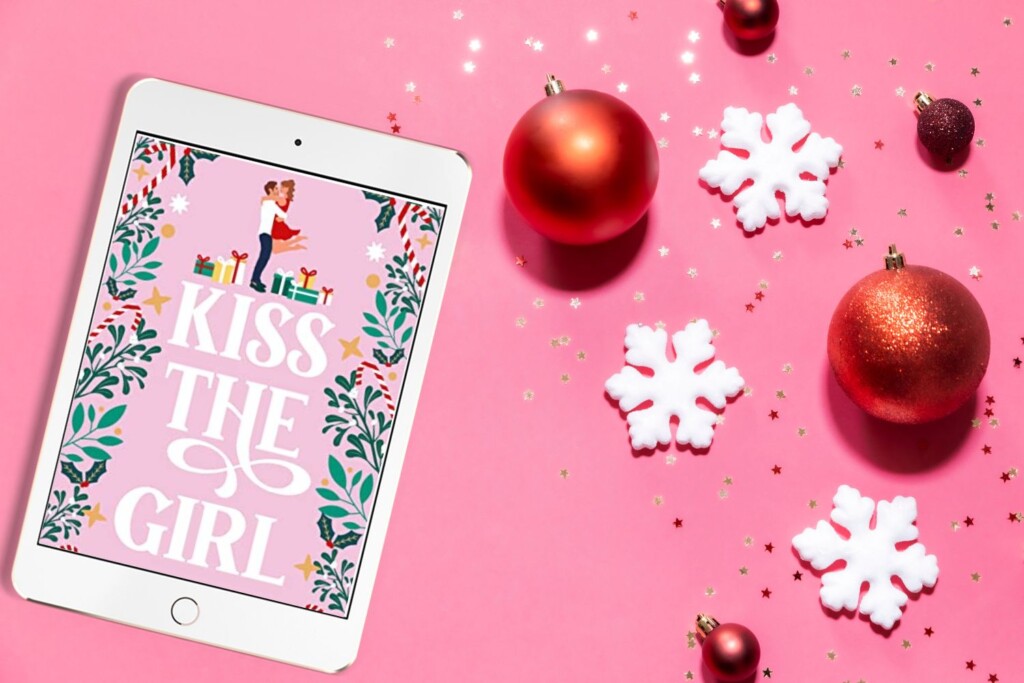 Flatlay with a bright pink background, red sparkly ornaments, white snowflakes, and a Kindle Unlimited Christmas Book cover on an iPad