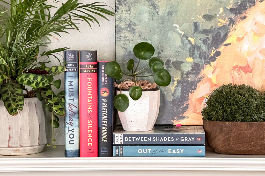 Ruta Sepetys Books on Fireplace mantel with plants