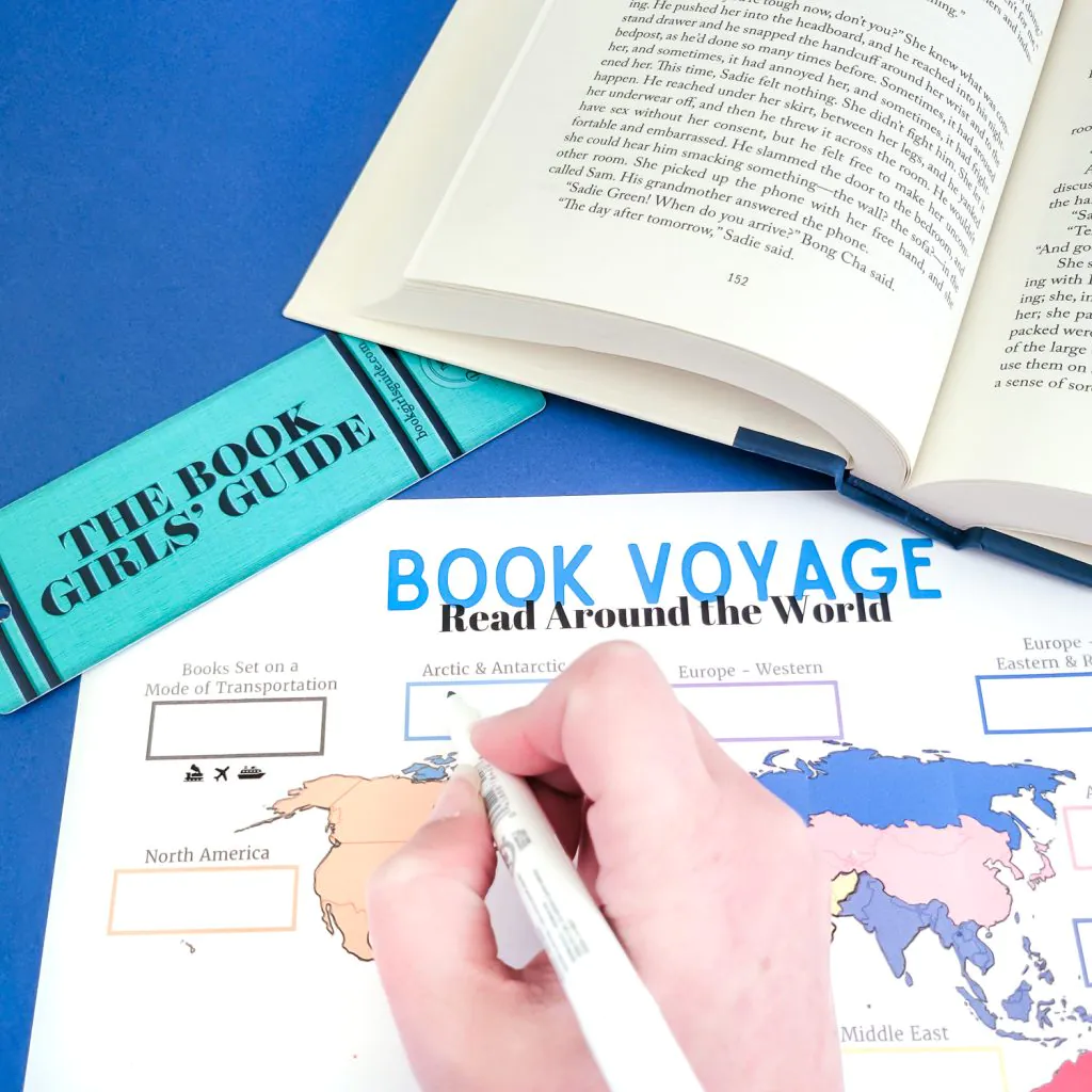 hand holding a pen writing on the Book Voyage printable world map book tracker