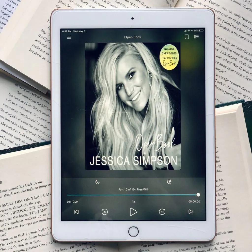 The audiobook of Jessica Simpson's memoir Open Book on an iPad screen. The iPad is sitting on top of a stack of open books.