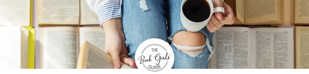 Woman sitting with an open book in one hand and coffee in the other hand, surrounded by a pile of open books