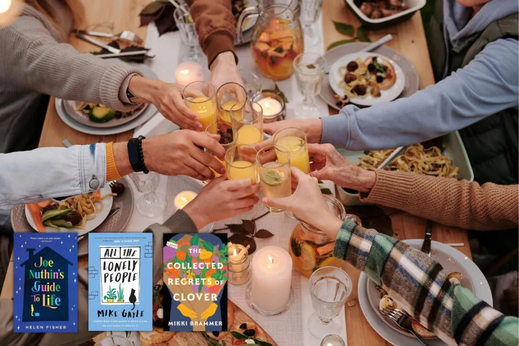 Many hands cheers-ing over a full table of food with 3 book covers