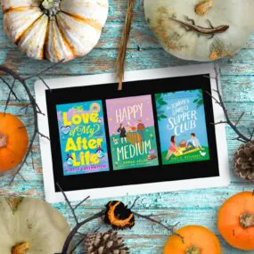 Pumpkins surrounding an ipad showing 3 halloween romance novels