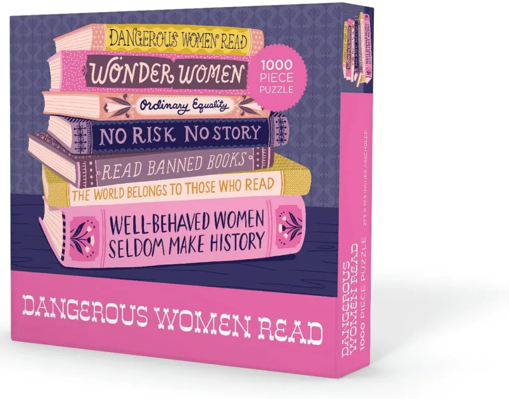 Puzzle in shades of pink and purple featuring a stack of books with titles that include "Dangerous Women Read" and "Read Banned Books"