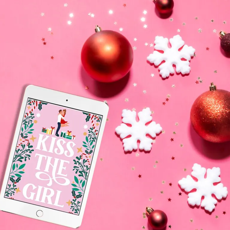 Flatlay with a bright pink background, red sparkly ornaments, white snowflakes, and a Kindle Unlimited Christmas Book cover on an iPad
